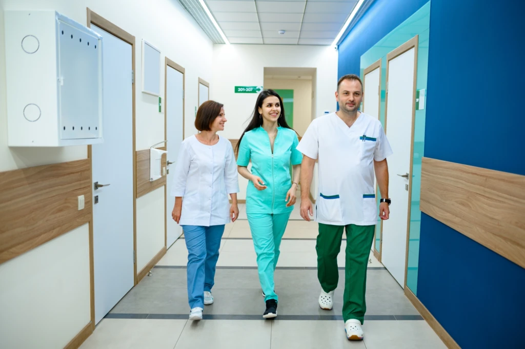 three-smiling-doctors-walking-in-clinic-corridor-2024-11-27-12-49-06-utc
